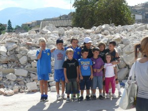 sullo sfondo le macerie della scuola di arischia